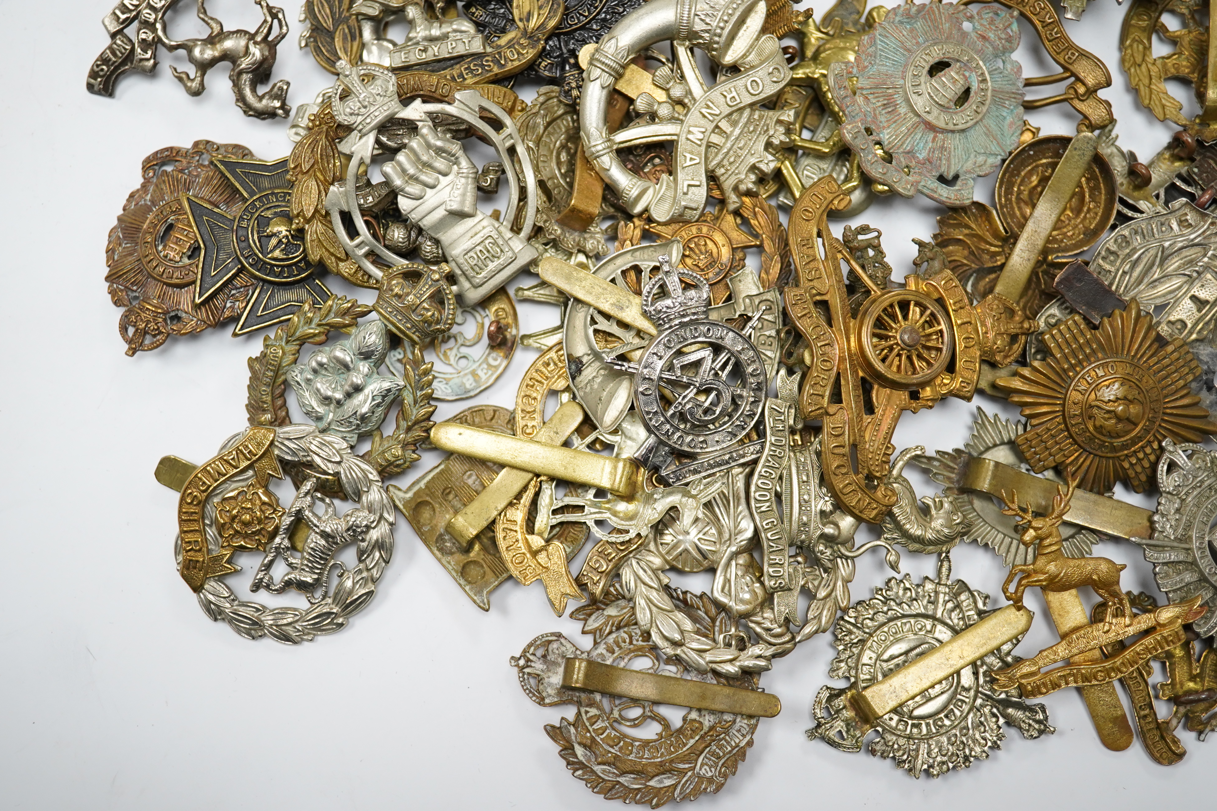 Sixty military cap badges, including; the Hampshire regiment, the South Lancashire Regiment, Prince of Wales Volunteers, the Tyneside Scottish Regiment, the Royal Artillery, the Norfolk Regiment, the Army Ordinance Corps